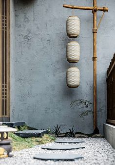 an outdoor area with two hanging lanterns on the wall and some rocks in the ground