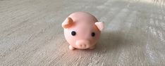 a small pink pig toy sitting on top of a wooden floor next to a window