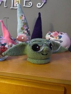 there is a crocheted yoda with glasses on top of the table next to other knitted items