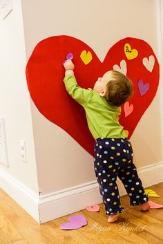 a toddler playing with a heart shaped wall decoration