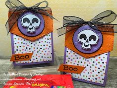 two halloween treat bags with candy in them, one has a skull on it and the other has a bow