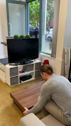 a person sitting on a couch in front of a tv with plants growing out of it