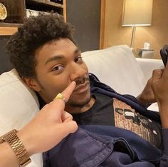 a man sitting on top of a couch holding a cell phone up to his face