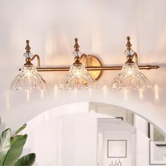 three light bathroom fixture with clear glass shades and brass finish, in an arched doorway