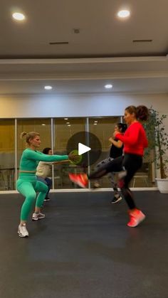 two women in green and red are doing exercises on an exercise mat while another woman watches