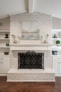 a white brick fireplace in a living room with wood flooring and built - in shelving