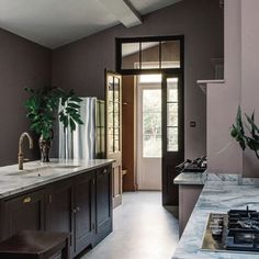 a kitchen with marble counter tops and dark wood cabinetry, along with an open door leading to the outside