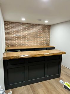 an empty room with two black bar stools and a brick wall in the background