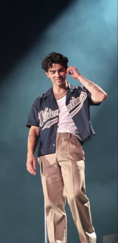 a man standing on top of a stage with his hands in his hair and wearing pants