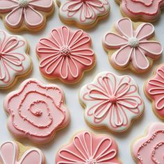 some pink and white decorated cookies are on a table with one cookie in the shape of a flower