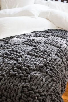 a large gray blanket sitting on top of a bed