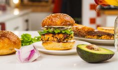 two burgers with lettuce, tomato and other ingredients on the counter top