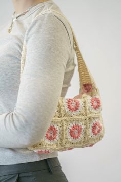 a woman is holding a crocheted purse