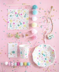 a table topped with paper plates and confetti on top of pink surface covered in confetti