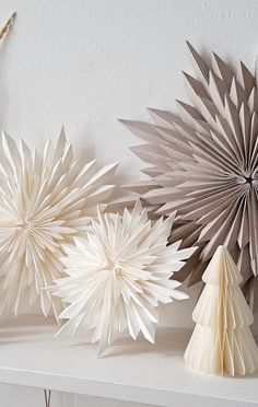 three paper snowflakes sitting on top of a white shelf