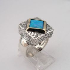 New ring from my collection. The ring is made of 925 hammered sterling silver with one square Blue Opal stone inlaid in polished 9k Yellow gold frame. Large and glittery, it is sure to be noticed. Don't miss! Material: Sterling Silver 925 , Yellow Gold 9K Gemstone: Blue Opal Front width: 15 mm / 0.590 in. Back width: 7 mm / 0.275 in. Size: 6 Lebeled and stamped 925. Will be sent to you in a modern recycled gift box. (All stains, if any, are due to camera.) Please feel free to contact us in any m Unique Hammered Rings For Formal Occasion, Yellow Gold Opal Ring, Handmade Wedding Band, Gold Opal Ring, Ring Blue Stone, Celebrity Engagement Rings, Ring Opal, Opal Ring Gold, Blue Stone Ring