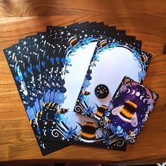 four cards with black and yellow designs on them sitting on a table next to a person's hand