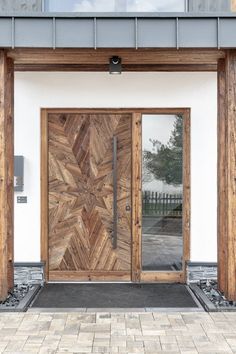 a large wooden door sitting on the side of a white wall next to a brick walkway