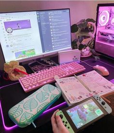 a person using a pink keyboard and mouse on a desk with two computer monitors behind them