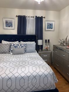 a bedroom with blue and white bedding, gray dressers and pictures on the wall