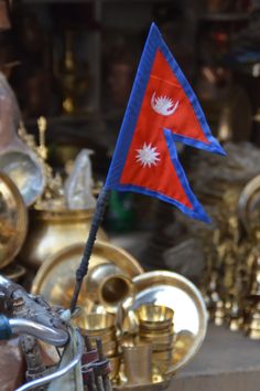 a red and blue flag is on a bike in front of other brass items that are behind it