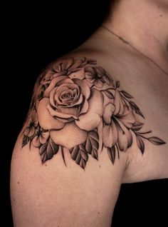 a woman's shoulder with a rose tattoo on it