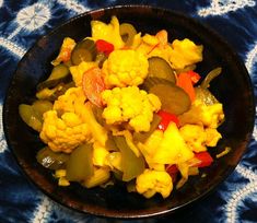 a black bowl filled with vegetables on top of a blue and white table cloth