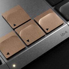 four square pieces of brown paper on top of a laptop keyboard