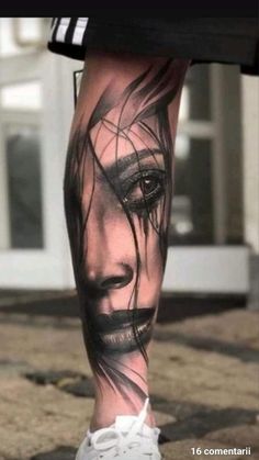 a woman's leg with a black and white face tattoo on the left side of her leg