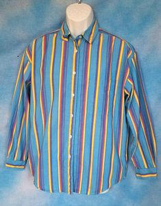 "Very streetwear right now. Loud bright thickly striped 80s cotton button down men's shirt in a color story of lagoon blue, dark blue, bright red and yellow. The sleeves are tapered - not quite batwing, but close - with tight cuffs. Wider more boxy/blousy fit. This was from a \"golf brand\" that I can't find any info on. So, a golf shirt, I guess. Excellent condition. Decade: 1980s Label: Mark, Fore and Strike Material: cotton Closure: buttons Vintage Condition: excellent (From a pet and smoke free home) Measurements are taken flat and doubled where necessary. I estimate this will best fit a size medium. Neck: 13.5\" Shoulder span: 19\" Sleeve length: 21.5\" Upper arm: 19.5\" Cuff: 6.5\" Bust: 45\" Length: 27.5\" NO RETURNS - ALL SALES ARE FINAL. Please check the measurements I've given, a Blue Vertical Stripes Button-up Shirt, Casual Blue Shirt With Vertical Stripes, Casual Blue Yarn-dyed Shirt, Retro Striped Button-up Shirt, Blue Yarn-dyed Cotton Shirt, Retro Long Sleeve Blue Shirt, Retro Blue Long Sleeve Shirt, Blue Retro Long Sleeve Shirt, 80s Aesthetic Outfits Men