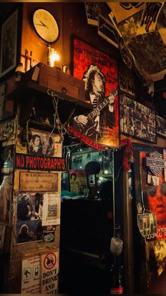 a room filled with lots of posters and pictures on the wall next to a clock