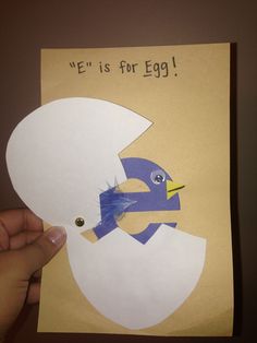 a hand holding up a piece of paper with an egg in the shape of a bird