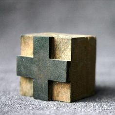 a small wooden cross sitting on top of a table next to a piece of wood