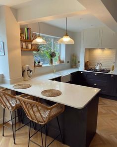 a kitchen with two bar stools next to an island in the middle of it