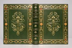 a green book with gold trimmings and decorative designs on the front cover is open