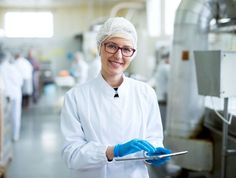 a woman in white coat and blue gloves holding a tablet