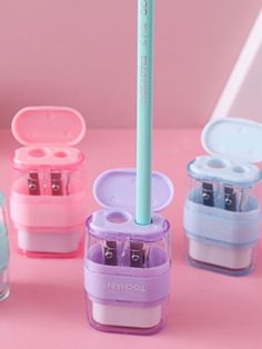 several small containers with pens in them on a pink surface next to a pencil holder