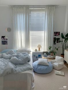 a bed room with a neatly made bed and pillows on the floor next to a window