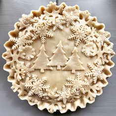 a pie crust decorated with snowflakes and trees