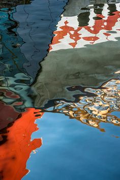 the reflection of an orange and white building in water with reflections on it's surface