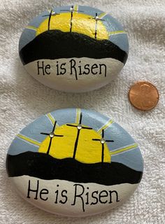 two painted rocks with the words he is risen and he is risen on them