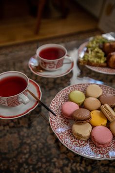 two plates filled with different types of cookies and pastries next to cups of tea