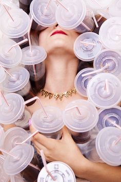 a woman is surrounded by plastic cups and straws