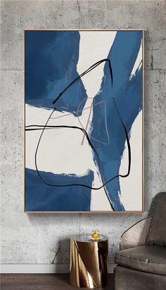 a blue and white abstract painting hanging on a wall above a chair in a living room