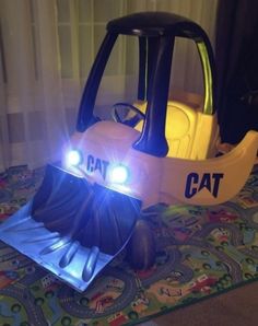 a toy car that is sitting on top of a rug with lights in the shape of a bulldozer