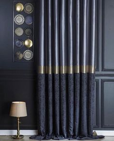 a black and gold curtain hanging on the side of a wall next to a lamp