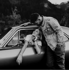 a man and woman leaning on the hood of a car