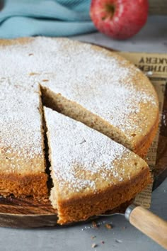 a cake that has been cut into pieces and is sitting on a plate with an apple in the background