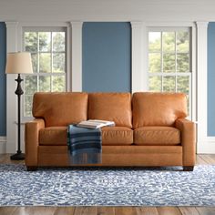 a tan leather couch sitting on top of a blue rug