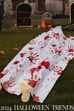 a white blanket with blood on it sitting in the grass next to tombstones and headstones